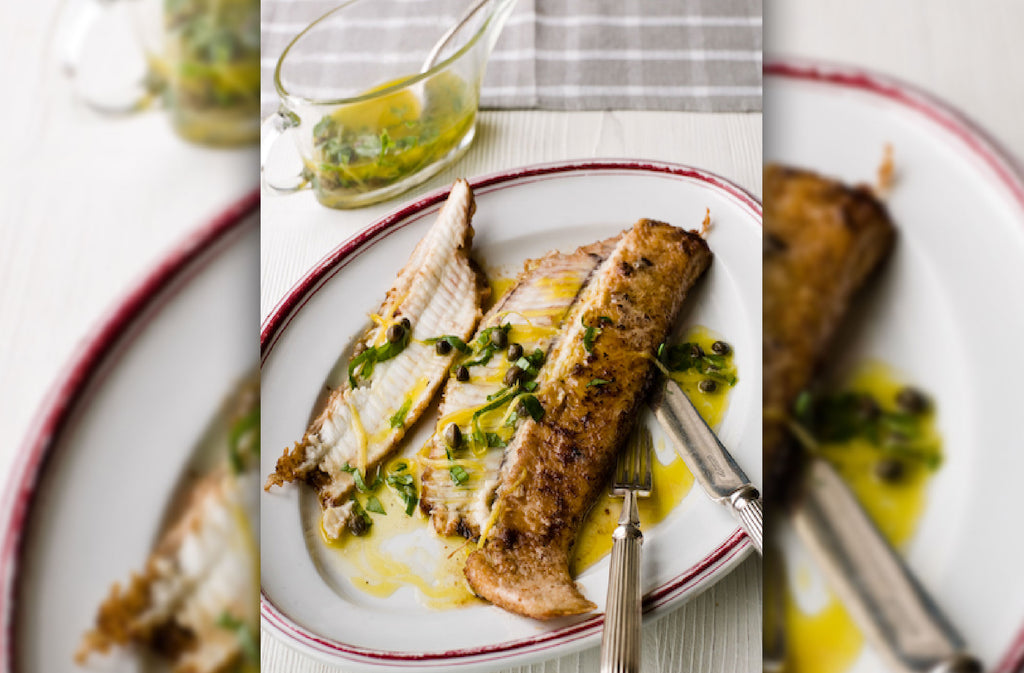 Plate containing grilled Rockfish Dover sole drizzled with lemon & caper dressing