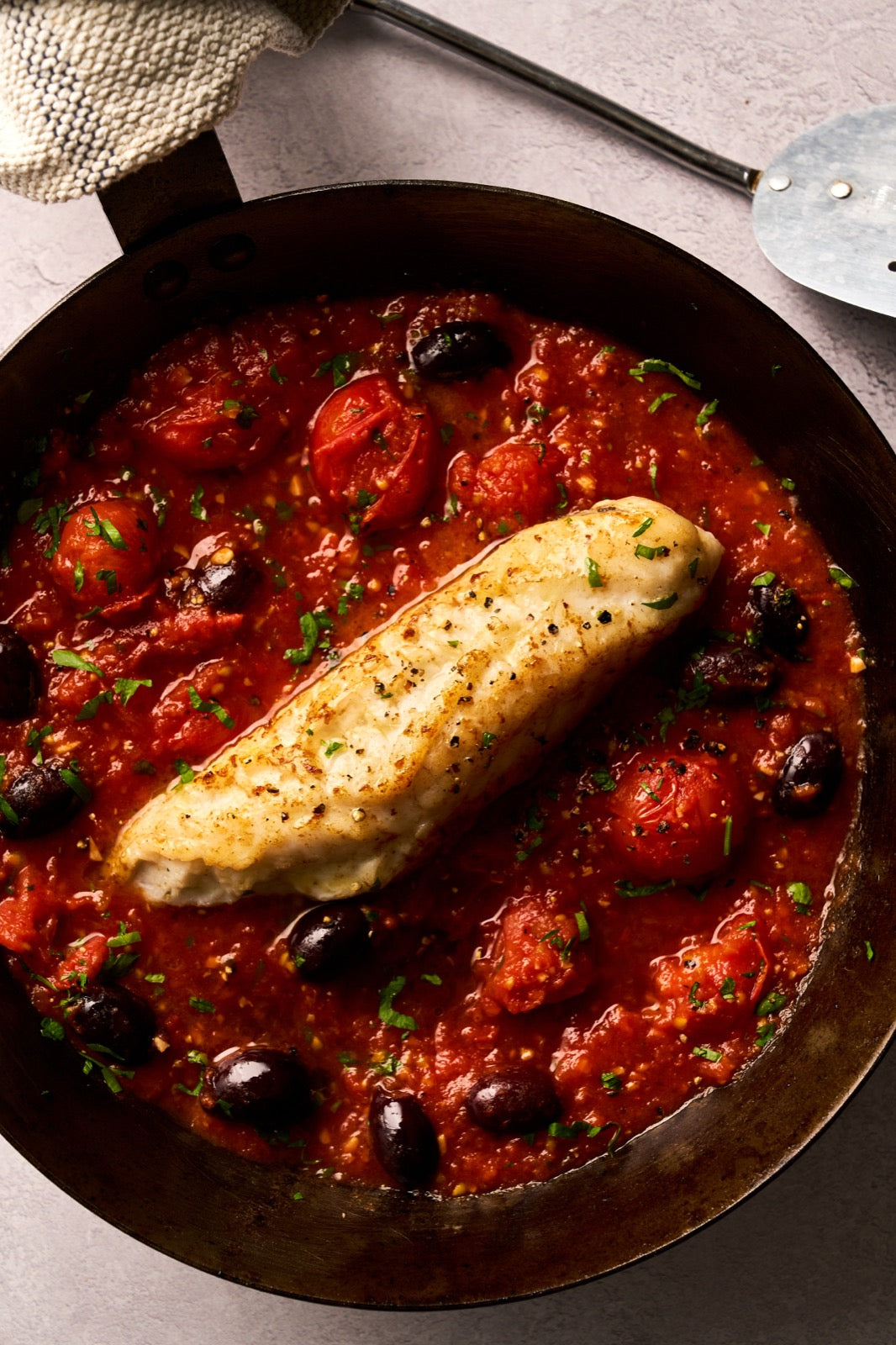 A portion of Monkfish fillet from Rockfish Online Seafood Market cooked in a pan with a rich tomato sauce around it