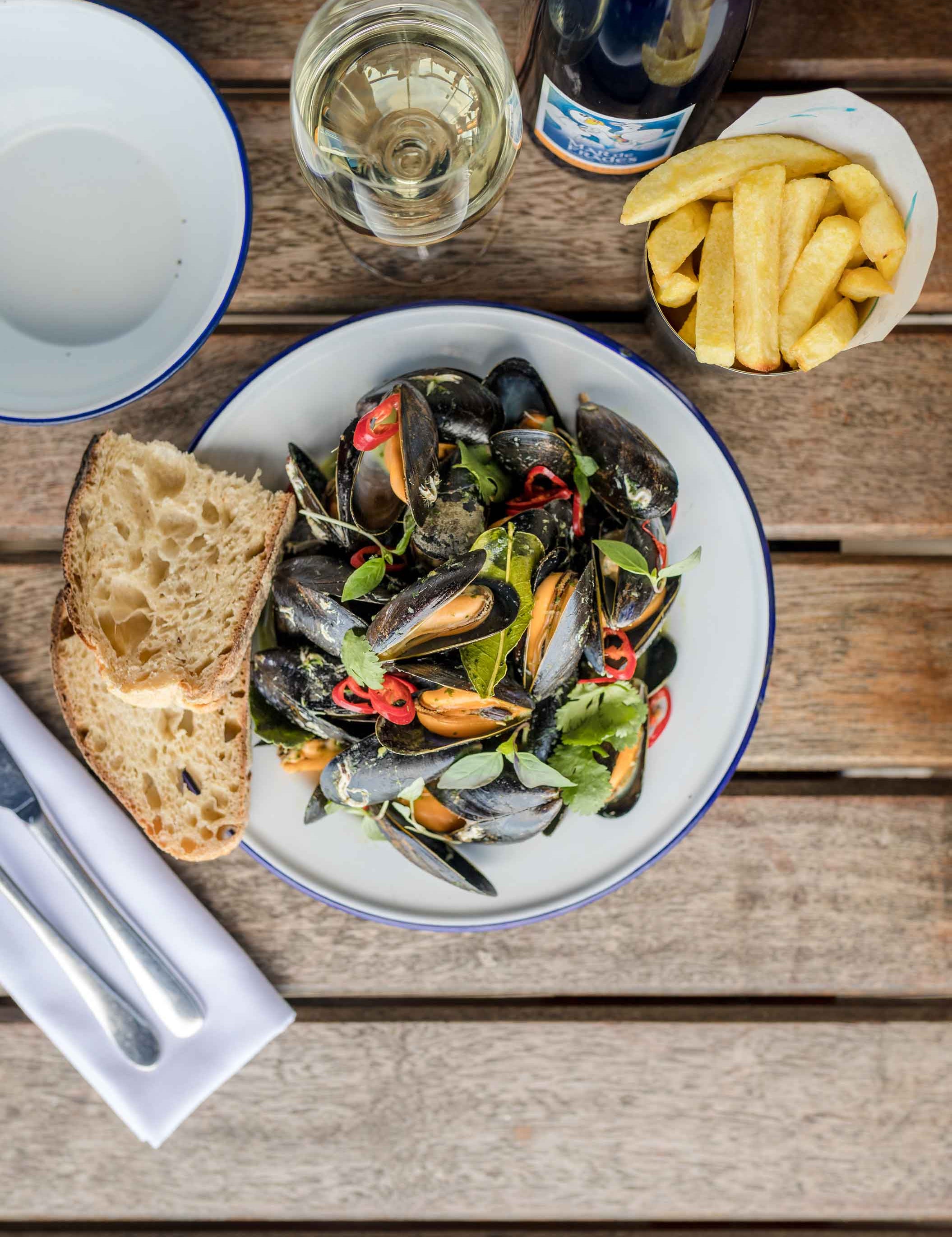 Plate of mussels with chilli, wine and bay. A side of bread and chips. Perfect with a glass of wine