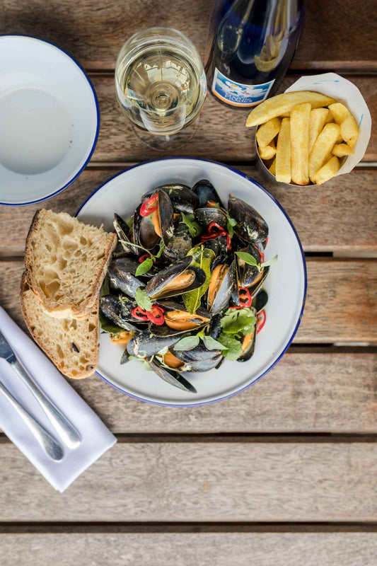 Plate of mussels with chilli, wine and bay. A side of bread and chips. Perfect with a glass of wine