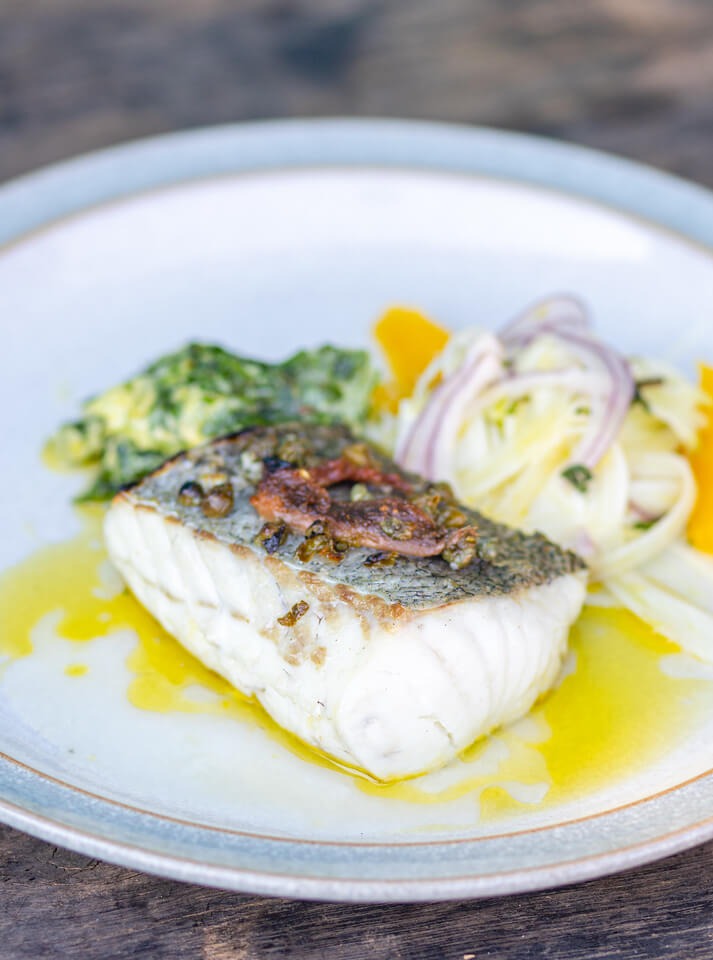 Pan fried Hake on a plate with a fresh salad on the side