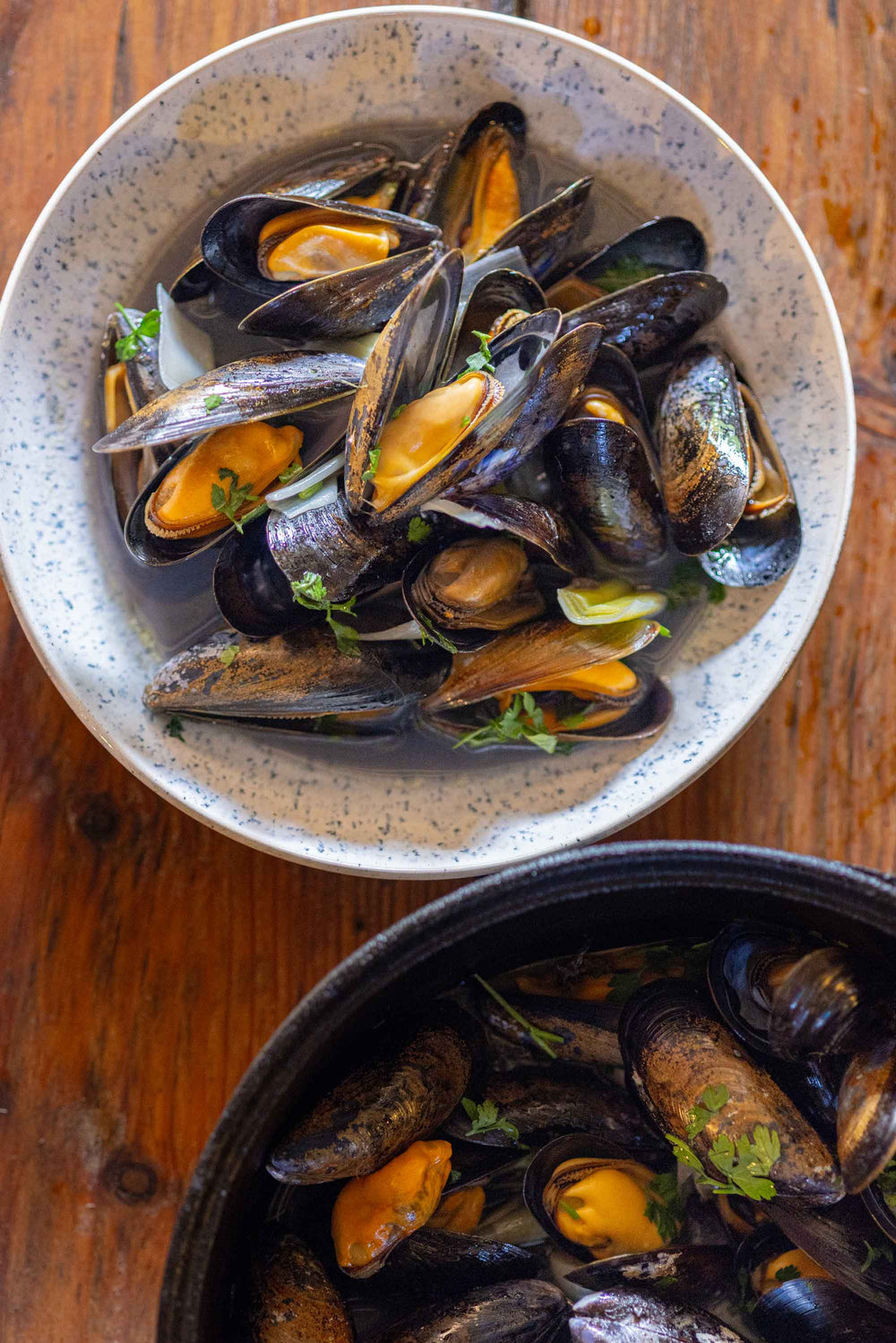 A bowl of mussels on a wooden table