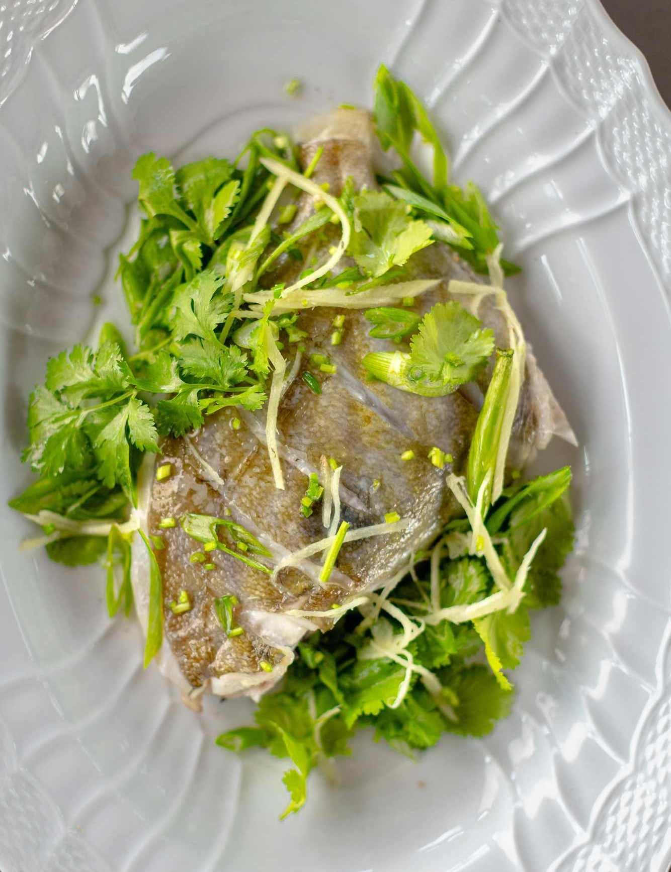John dory on the bone from Rockfish online seafood market - fresh john dory delivered direct from the coast across the UK the next day. A portion o the bone on a bed of herbs