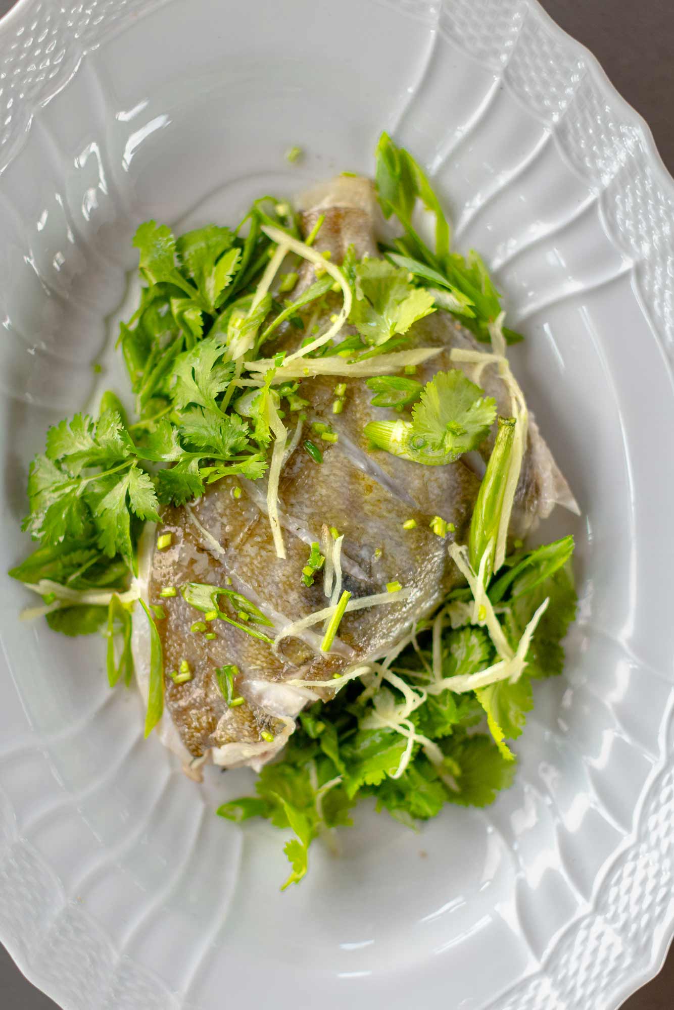 John dory on the bone from Rockfish online seafood market - fresh john dory delivered direct from the coast across the UK the next day. A portion o the bone on a bed of herbs