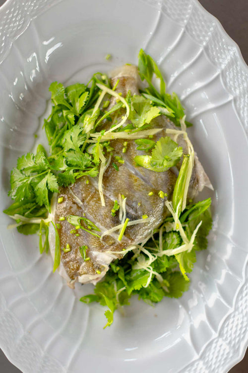 John dory on the bone from Rockfish online seafood market - fresh john dory delivered direct from the coast across the UK the next day. A portion o the bone on a bed of herbs