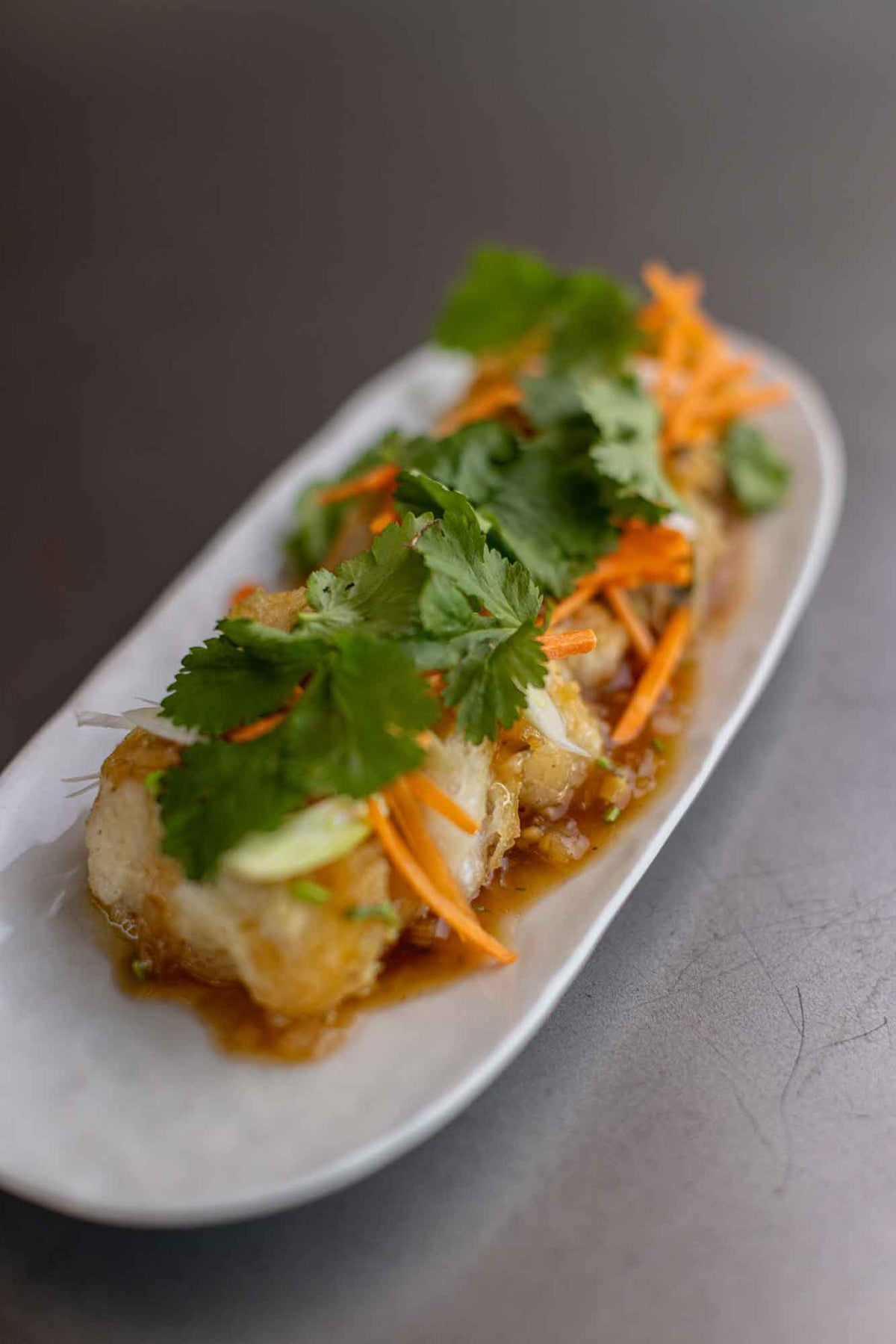 Fried monkfish cheeks with a sauce. Garnished with carrot and coriander