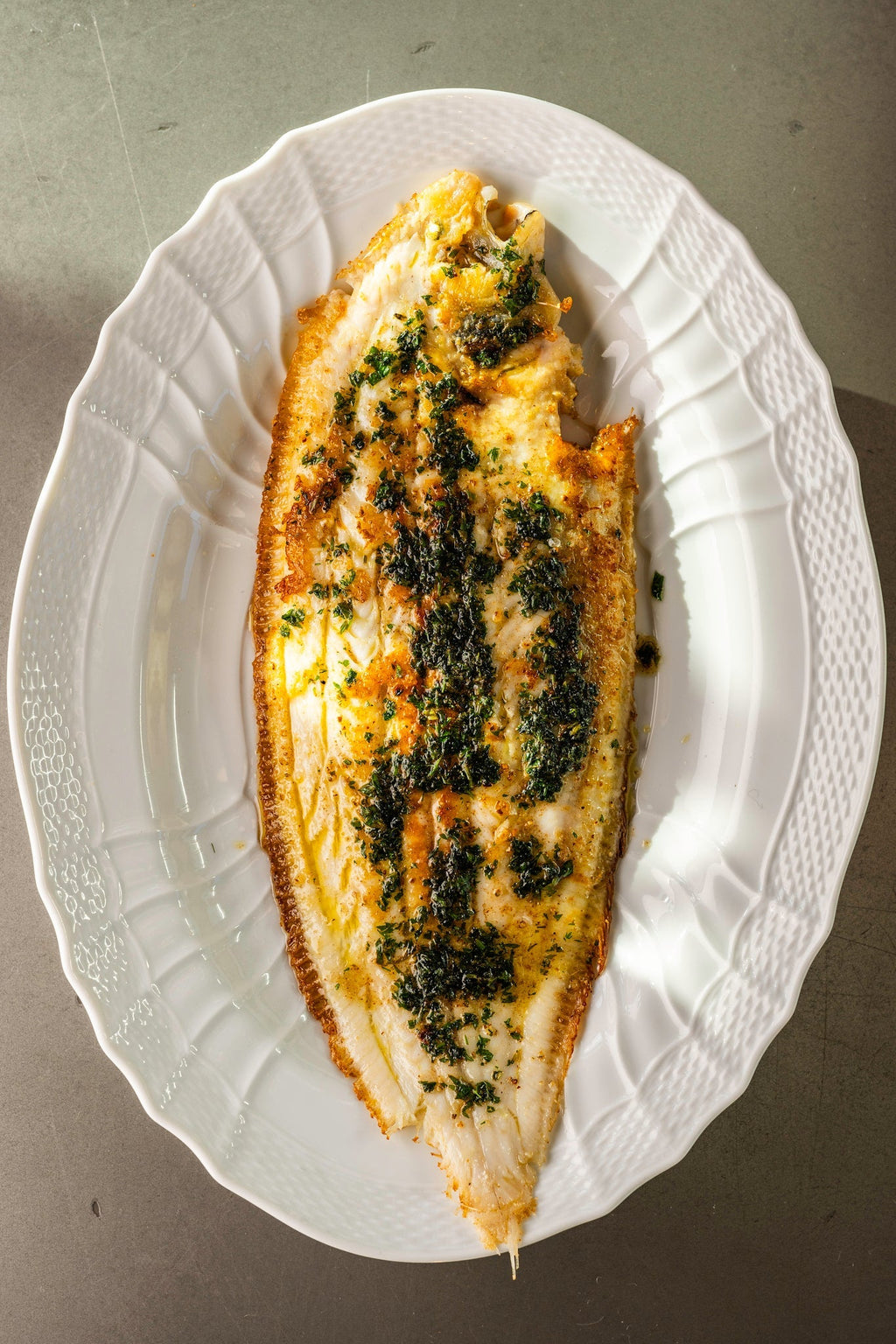 A cooked Dover Sole Meunière on a white plate