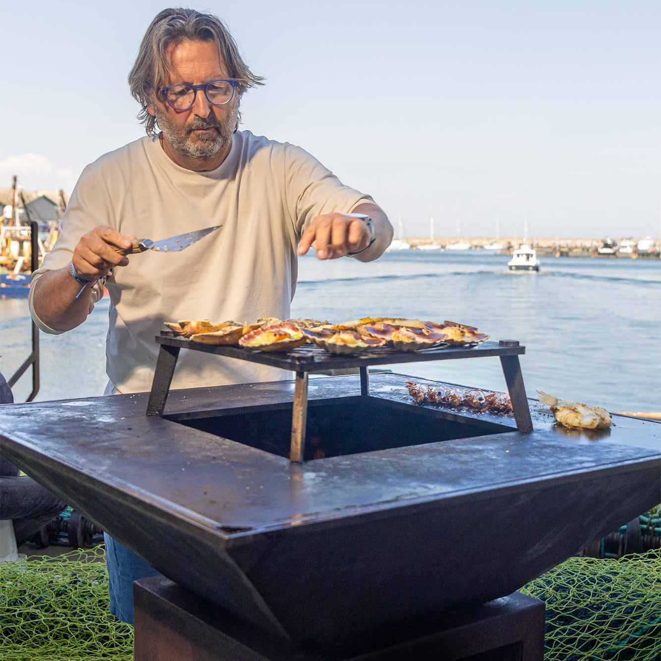 Mitch cooking on a Vulcanus BBQ in front of Brixham harbour