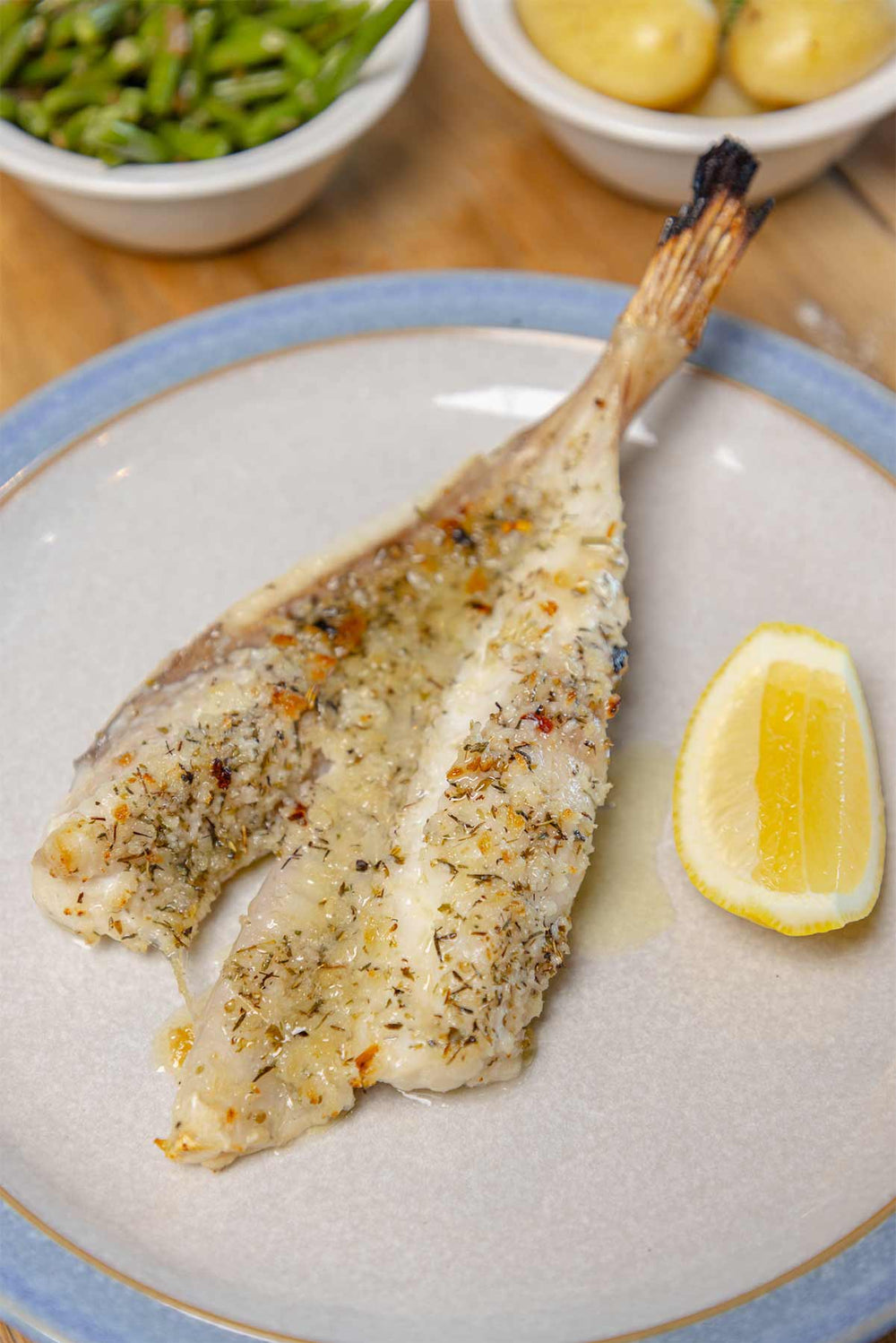 Monkfish as grilled in Romagna by Rockfish on a table with green beans and new potatoes in the top of the frame