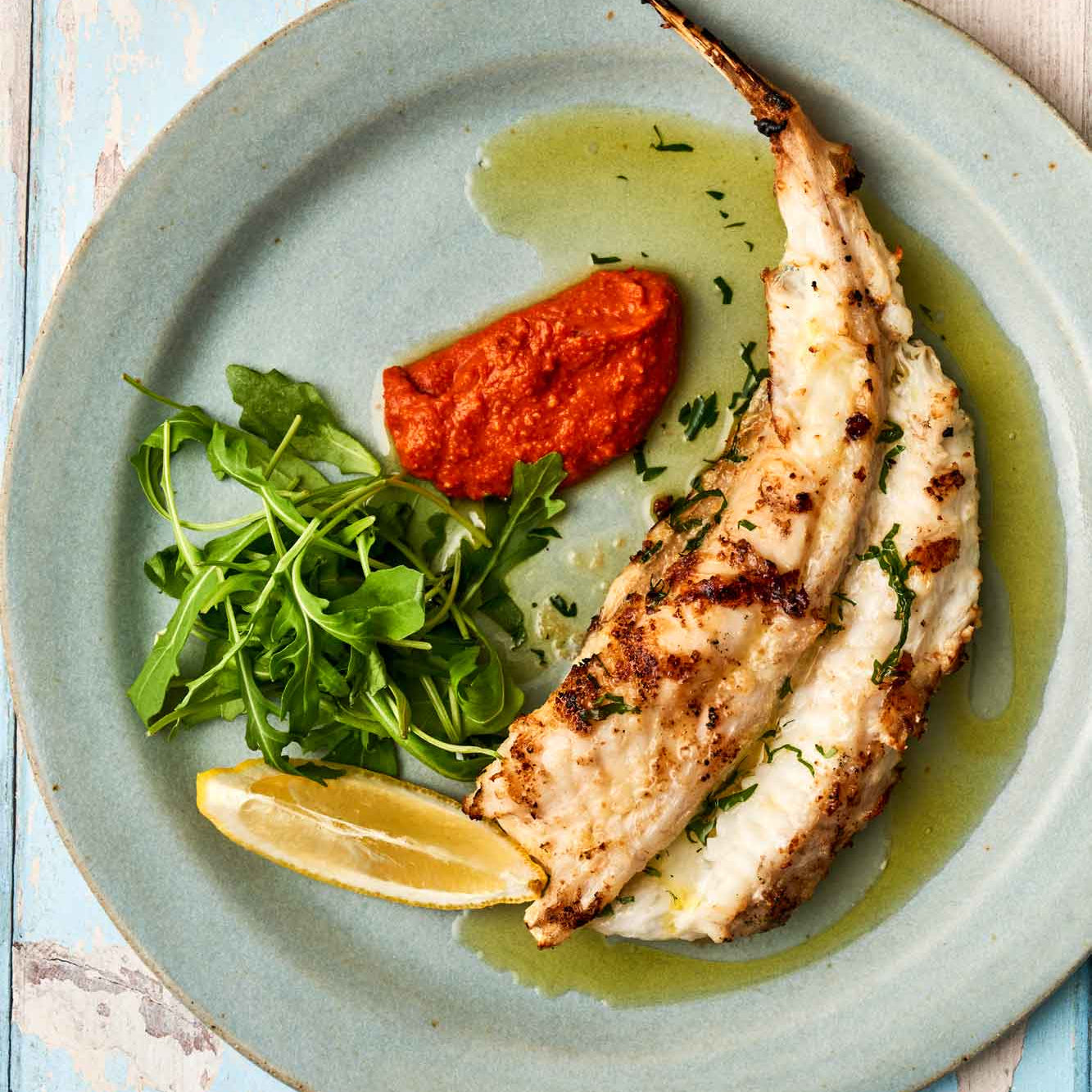 Monkfish tail on. a plate with romesco sauce and rocket