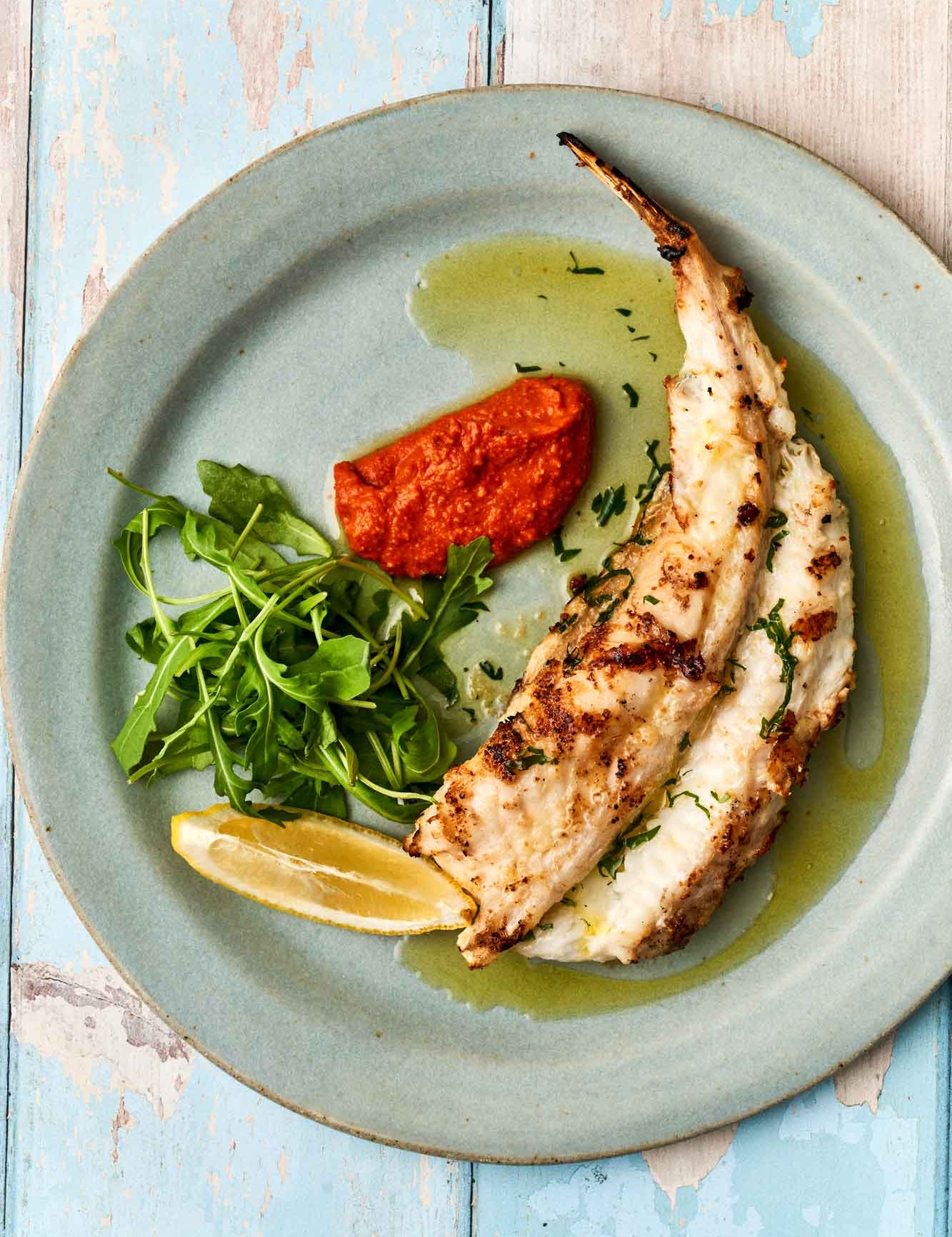 Monkfish tail on. a plate with romesco sauce and rocket