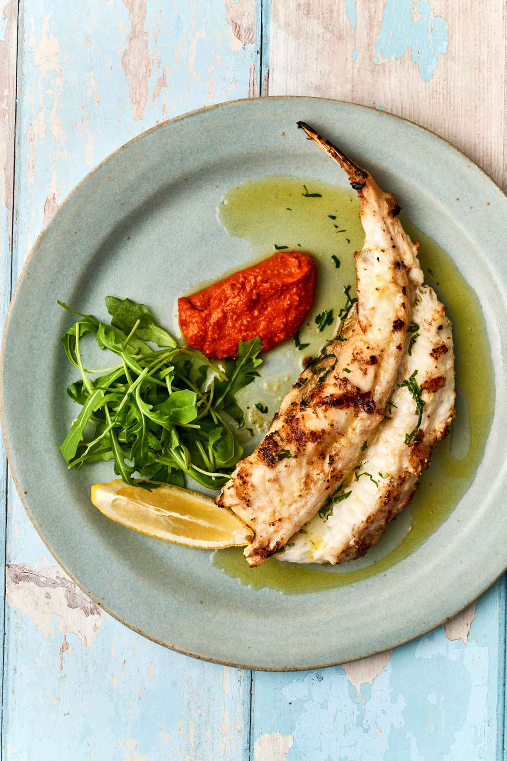 Monkfish tail on. a plate with romesco sauce and rocket