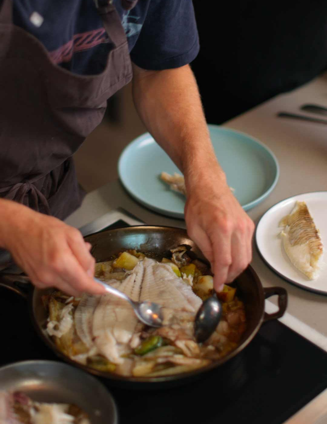 Alfie Turner filleting whole turbot to share out of a cast iron skillet. 