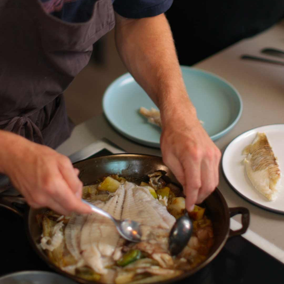 Alfie Turner filleting whole turbot to share out of a cast iron skillet. 