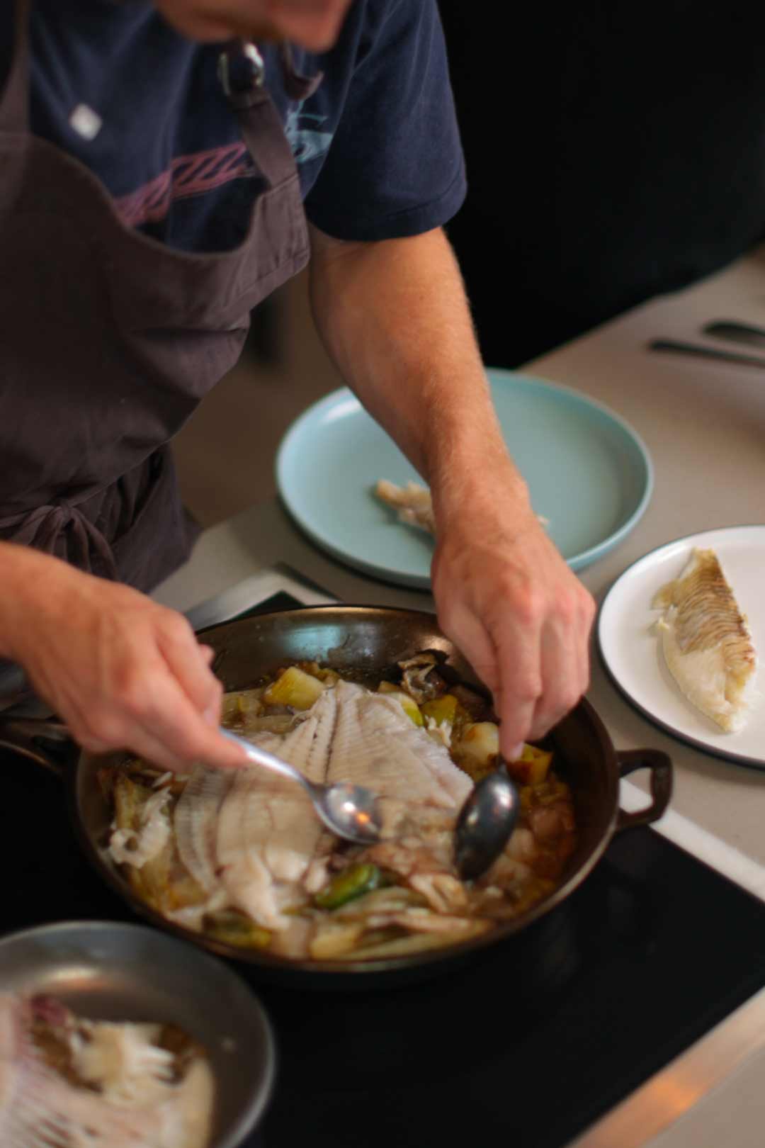 Alfie Turner filleting whole turbot to share out of a cast iron skillet. 
