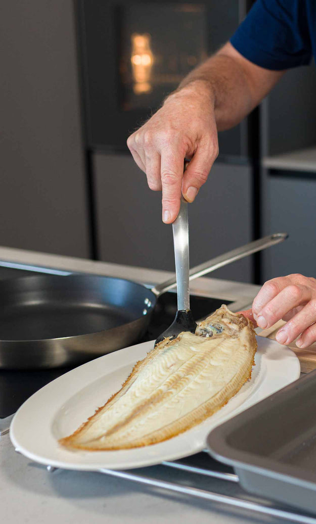 A dover sole being plated after being cooked in the frying pan