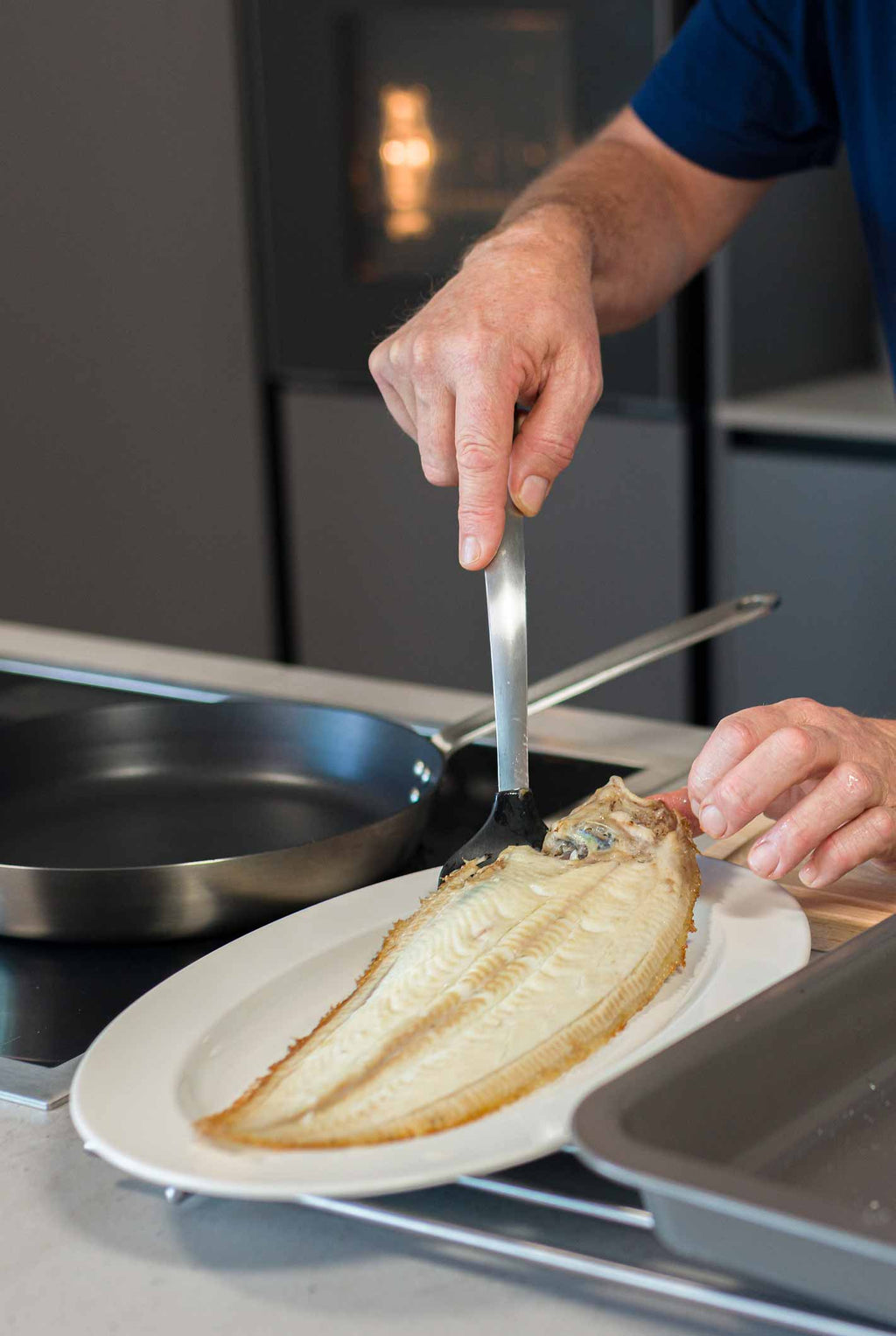 A dover sole being plated after being cooked in the frying pan