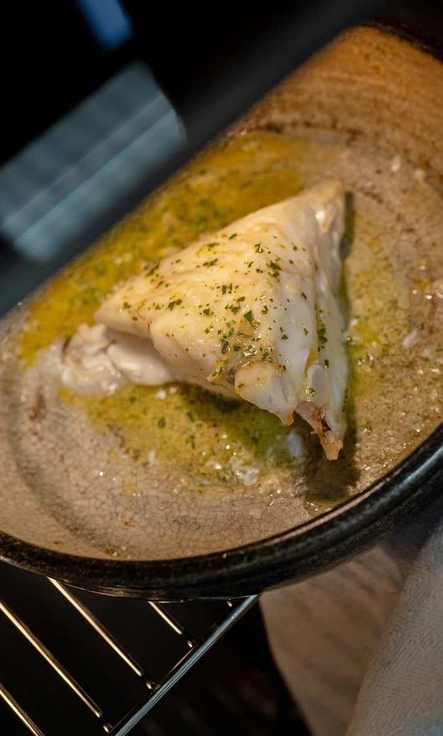 Piece of Turbot being cooked in an oven with garlic butter