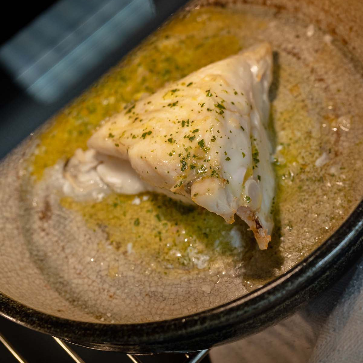 Piece of Turbot being cooked in an oven with garlic butter