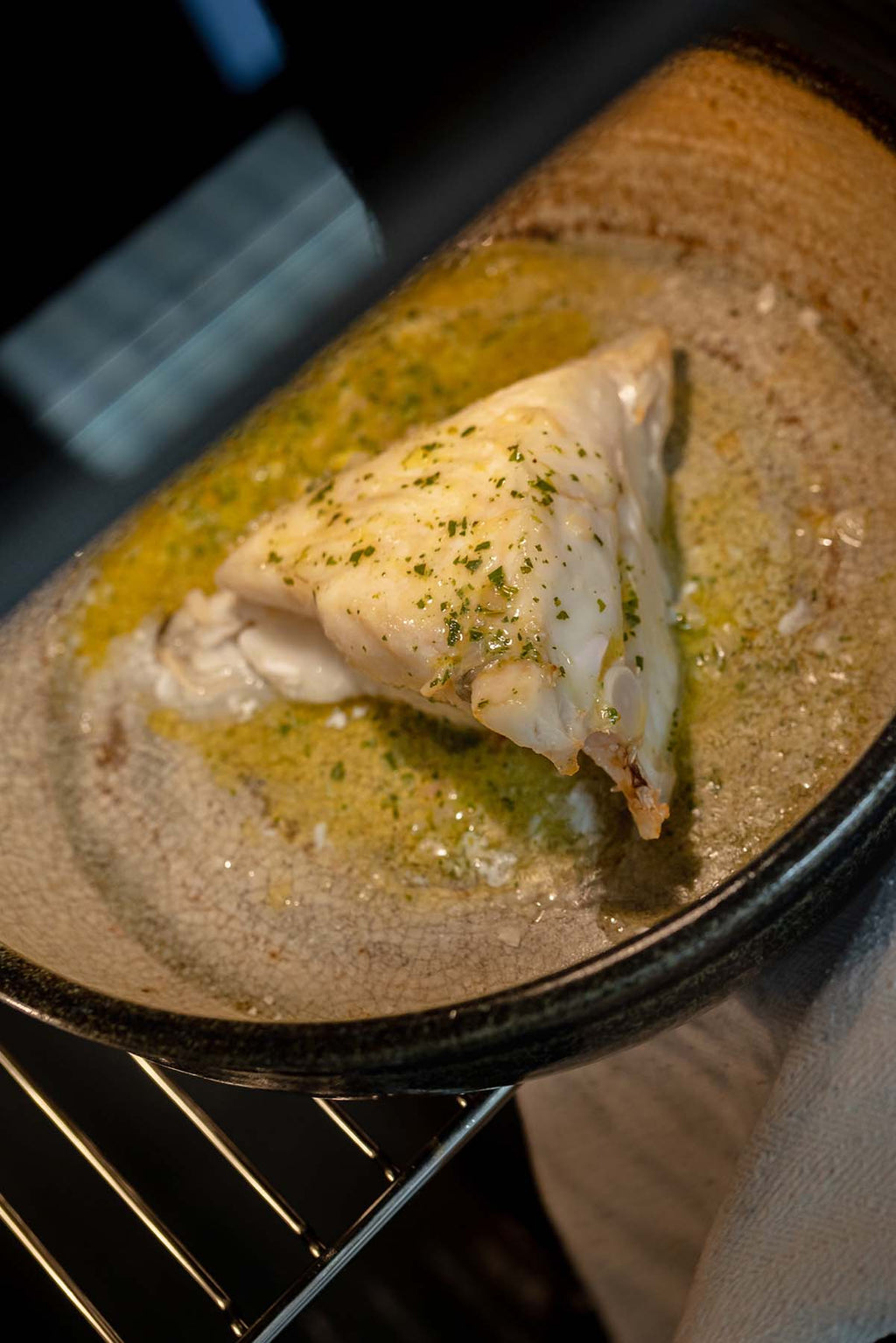 Piece of Turbot being cooked in an oven with garlic butter