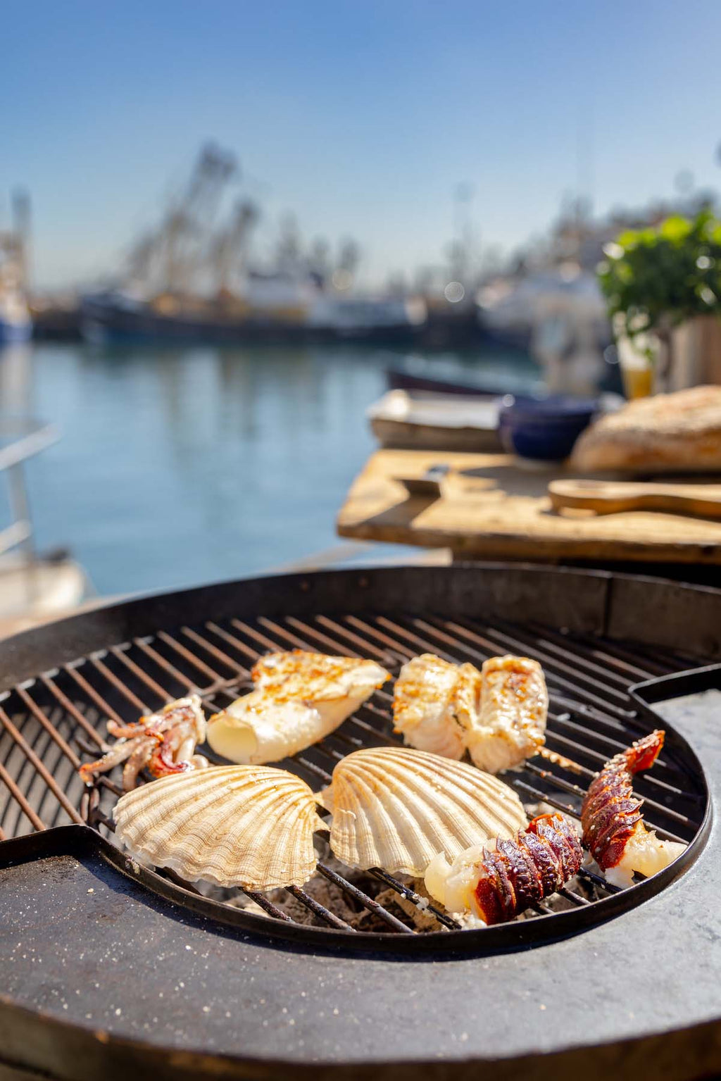 Seafood including scallops, lobster tail, squid and monkfish being cooked on a bbq at Brixham quayside