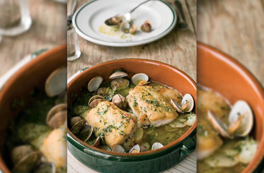 Two Rockfish hake fillets in a dish with sauce and clams