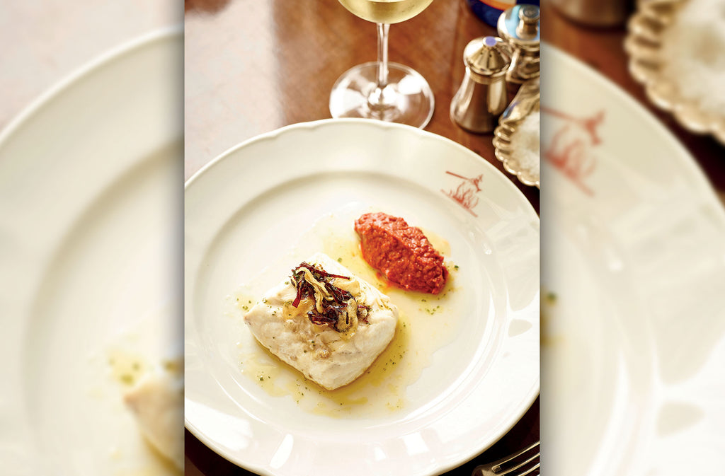 A Rockfish fillet on a plate with Romesco sauce next to it