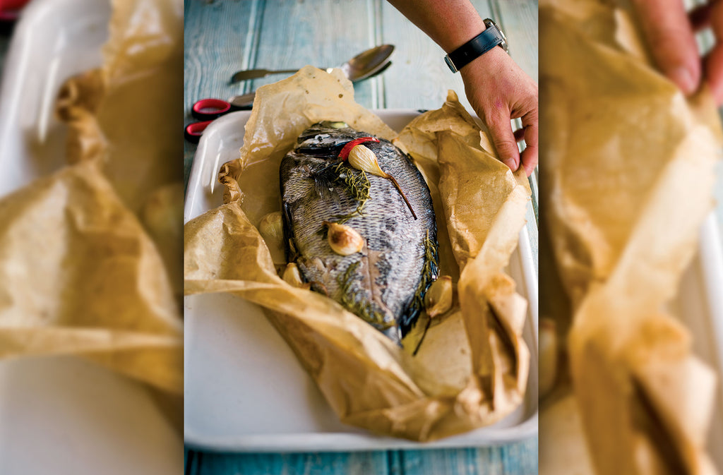 Baked Sea Bream in parchment paper with sprigs of rosemary and garlic