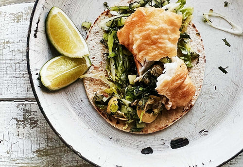Crisp fried fish taco with lime wedges on the side