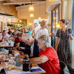 People dining at a Rckfish restaurant with a server and patrons in the background.