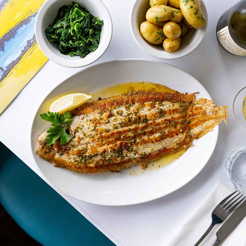 Dover Sole with a side of potatoes and spinach on a table at Rockfish seafood restaurant