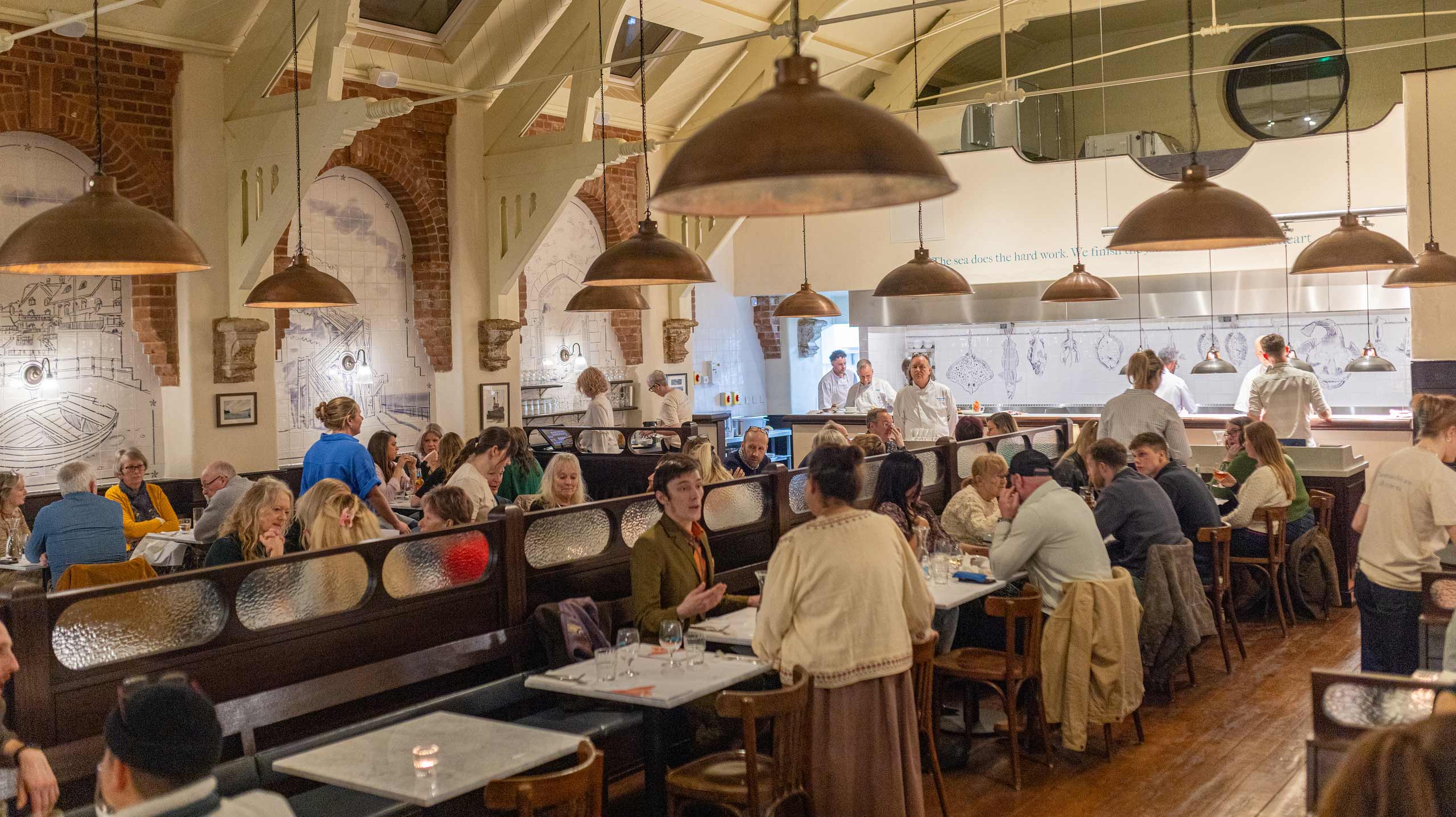 Rockfish Sidmouth dining room filled with guests being served and chefs cooking in the background