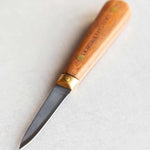 A small oyster knife with a light brown wooden handle and a dark steel blade, shown on a light gray textured background. The handle features the brand name 'Dorset Oysters' engraved vertically.