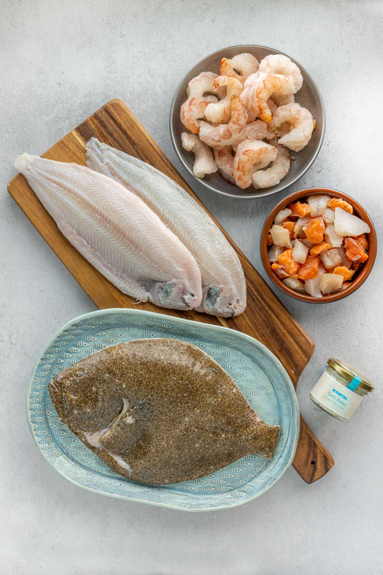 Turbot to share on a plate. 2 Dover Sole on a board. Prawns and fish pie mic in bowls and a garlic butter