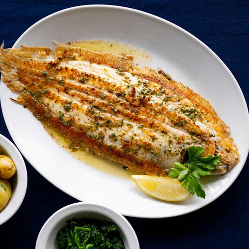 Dover Sole cooked on a plate with a side of spinach and new potatoes