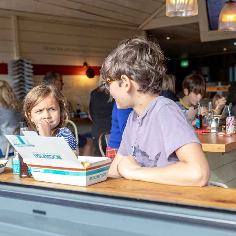 Two children enjoying Rockfish takeaway at Rockfish Brixham takeaway