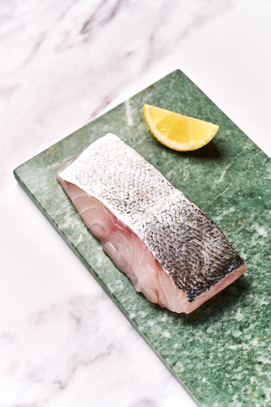 A portion of Coley fillet from Rockfish Online Seafood Market on a piece of marble.