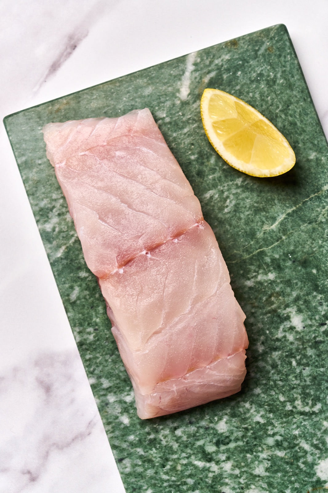 A portion of Coley fillet from Rockfish Online Seafood Market on a piece of marble.