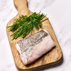 A portion of Hake fillet from Rockfish Online Seafood Market on a wooden board
