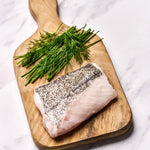 A portion of Hake fillet from Rockfish Online Seafood Market on a wooden board