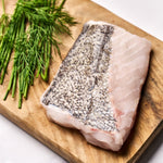 A portion of Hake fillet from Rockfish Online Seafood Market on a wooden board