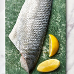 A portion of Sea Bass fillet skin side up from Rockfish Online Seafood Market on a piece of marble.