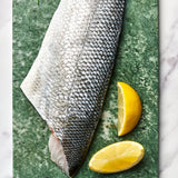 A portion of Sea Bass fillet skin side up from Rockfish Online Seafood Market on a piece of marble.
