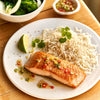 A portion of Salmon from Rockfish Online Seafood Market cooked on a plate next to some rice.