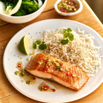 A portion of Salmon from Rockfish Online Seafood Market cooked on a plate next to some rice.