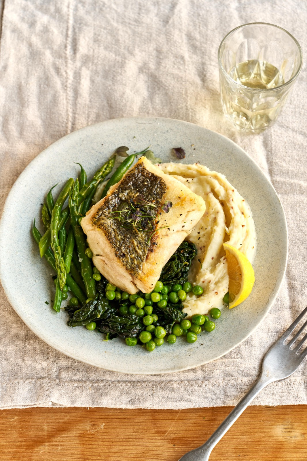 A portion of Hake fillet from Rockfish Online Seafood Market cooked on  plate with a side of mash and some greens.