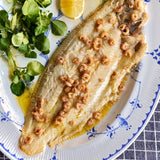 A portion of Sand Sole from Rockfish Online Seafood Market cooked and arranged on a plate with potted shrimp and crest on the side 