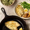 A portion of Lemon Sole fillets from Rockfish Online Seafood Market in a cast iron skillet and on a plate next to it with potato and greens.