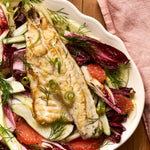 A portion of Seabass fillet from Rockfish Online Seafood Market cooked and nestled on a fresh slaad