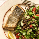 A portion of Coley fillet from Rockfish Online Seafood Market cooked on a plate next to a healthy salad.
